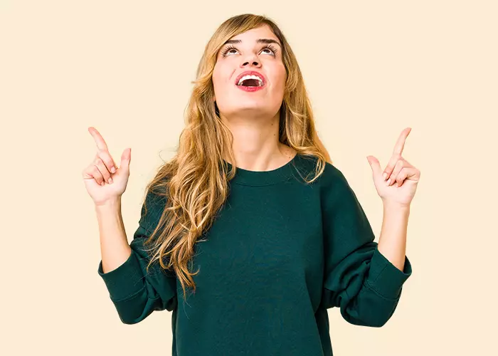 Woman on orange background pointing upwards